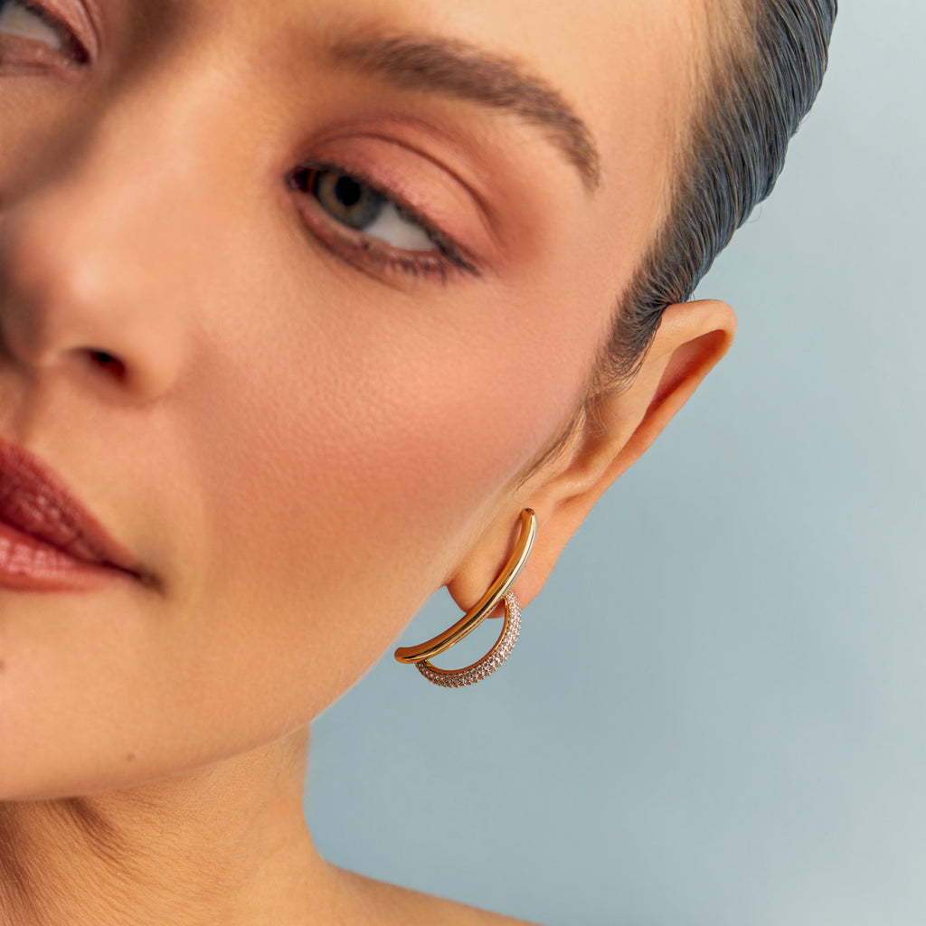 Woman wearing elegant 18K gold-plated curved earrings with pavé zirconia.