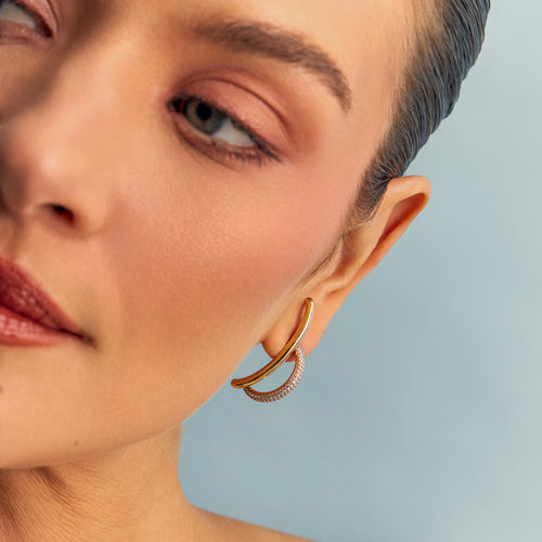 Woman wearing elegant 18K gold-plated curved earrings with pavé zirconia.