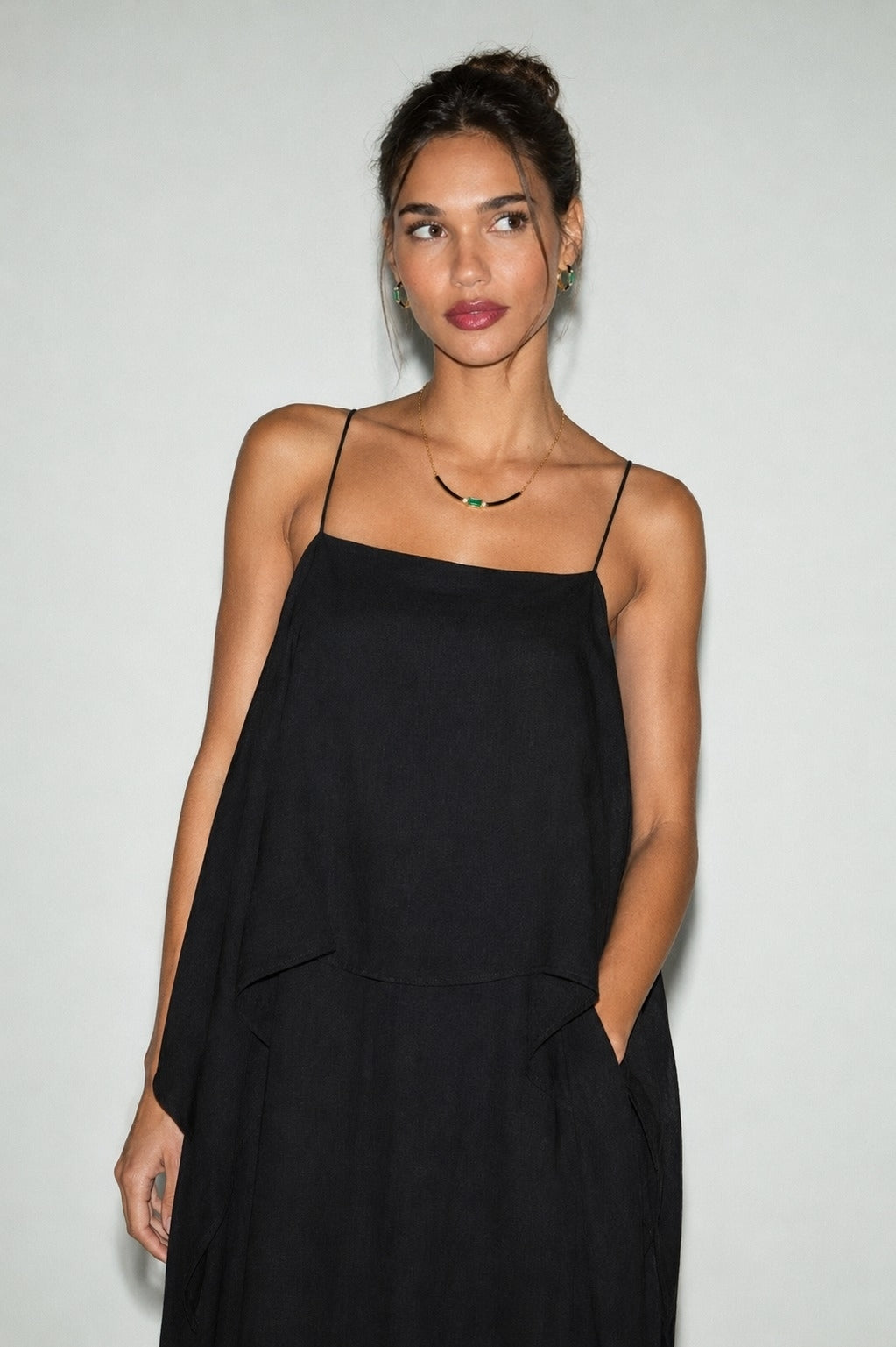 Woman wearing a black slip dress against a plain background