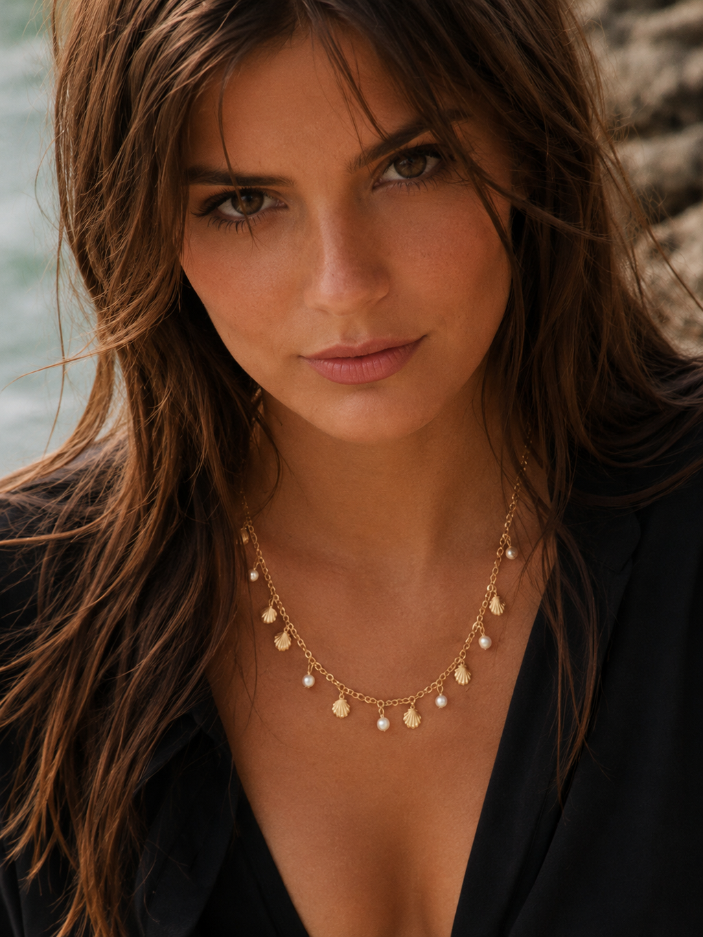 Woman wearing a gold necklace with a scenic background