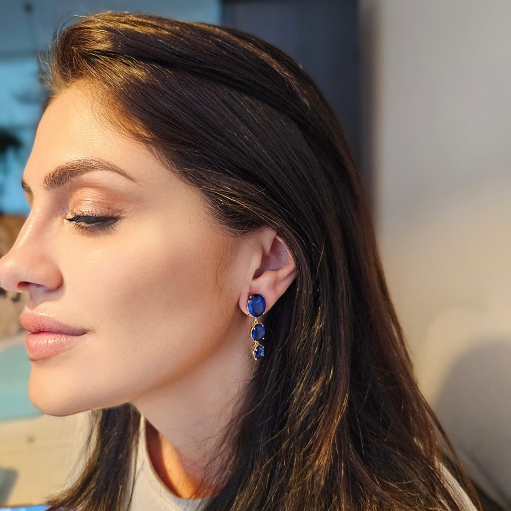 Close-up of a woman wearing blue earrings with a blurred background