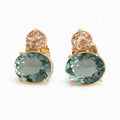 Pair of earrings with green gemstones and gold accents on a white background