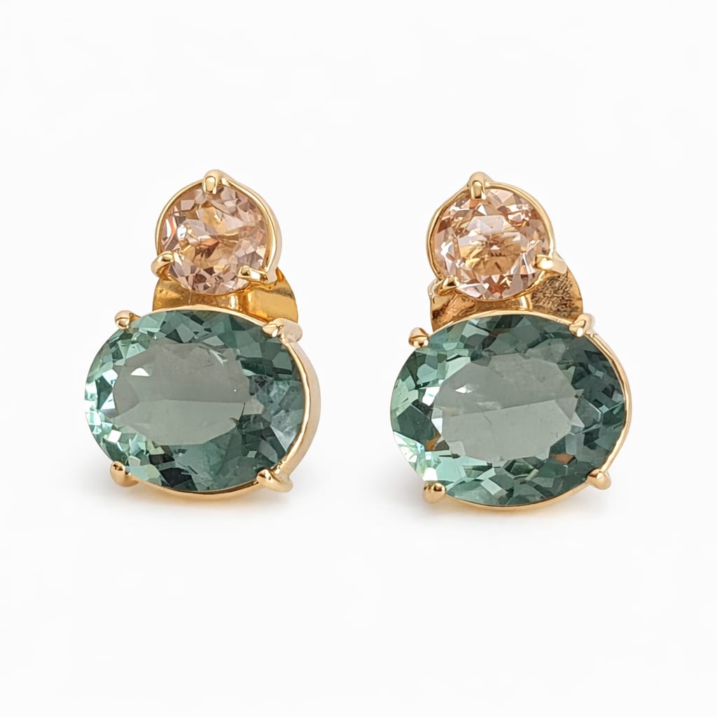 Pair of earrings with green gemstones and gold accents on a white background