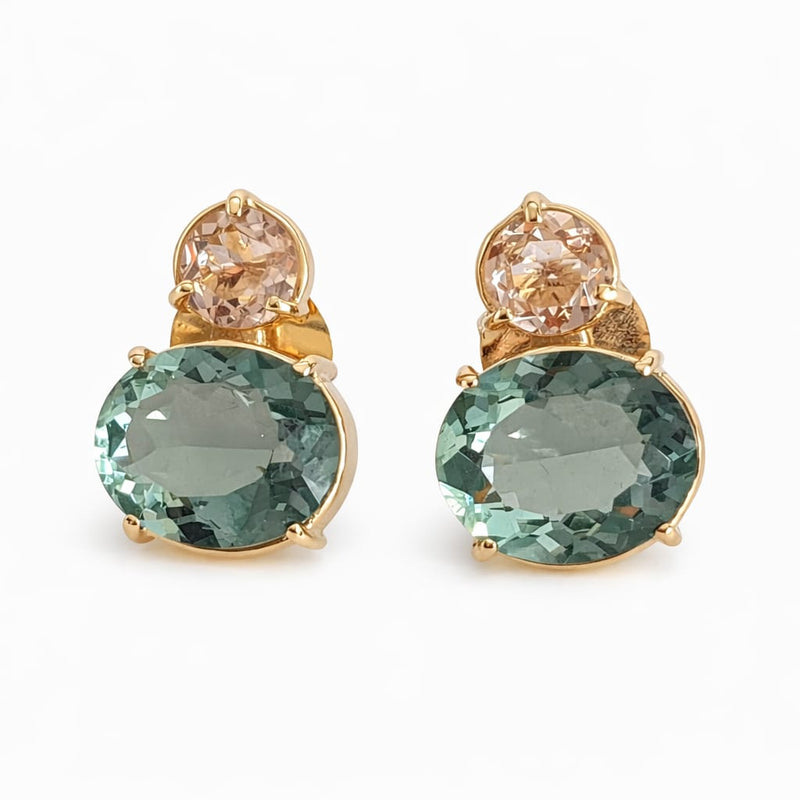 Pair of earrings with green gemstones and gold accents on a white background