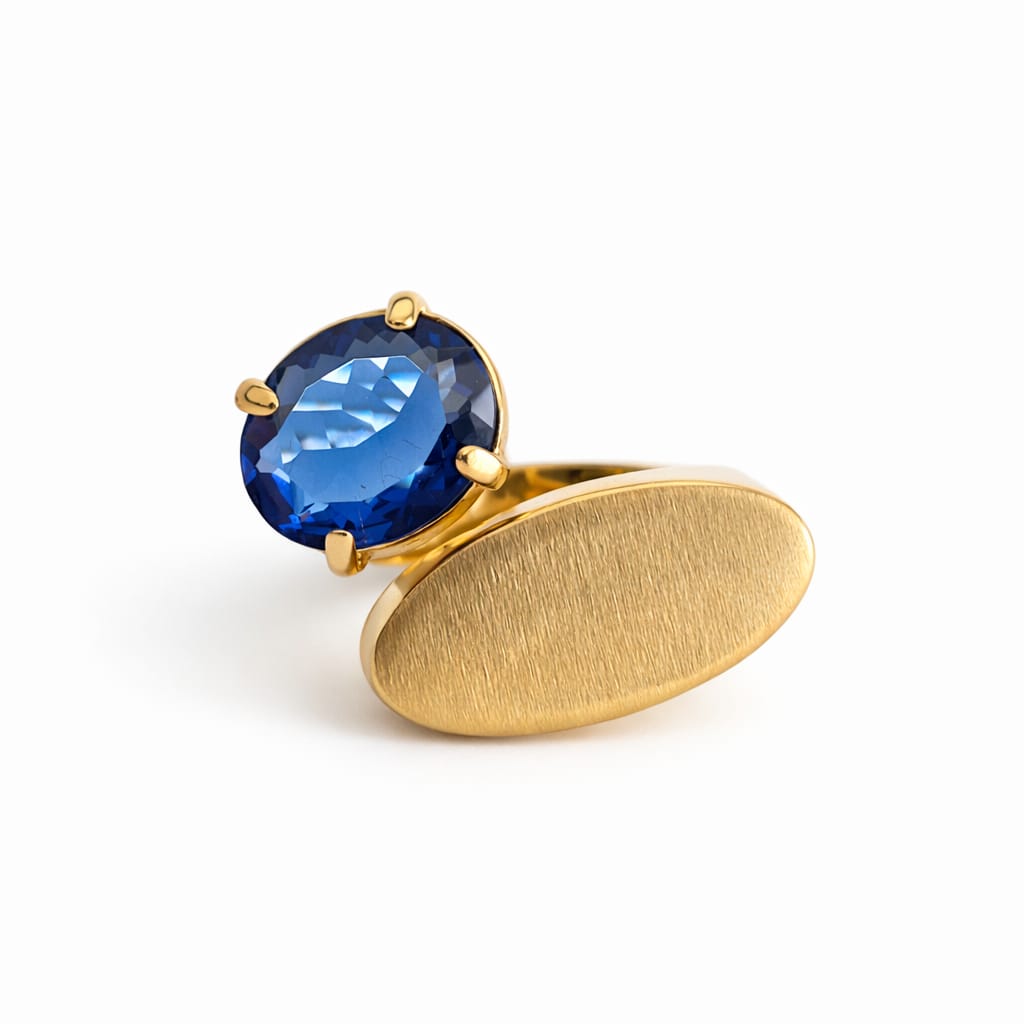 Gold ring with a blue gemstone on a white background
